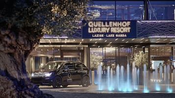 A luxury resort entrance with a car parked in front, a signboard, and a fountain display.
