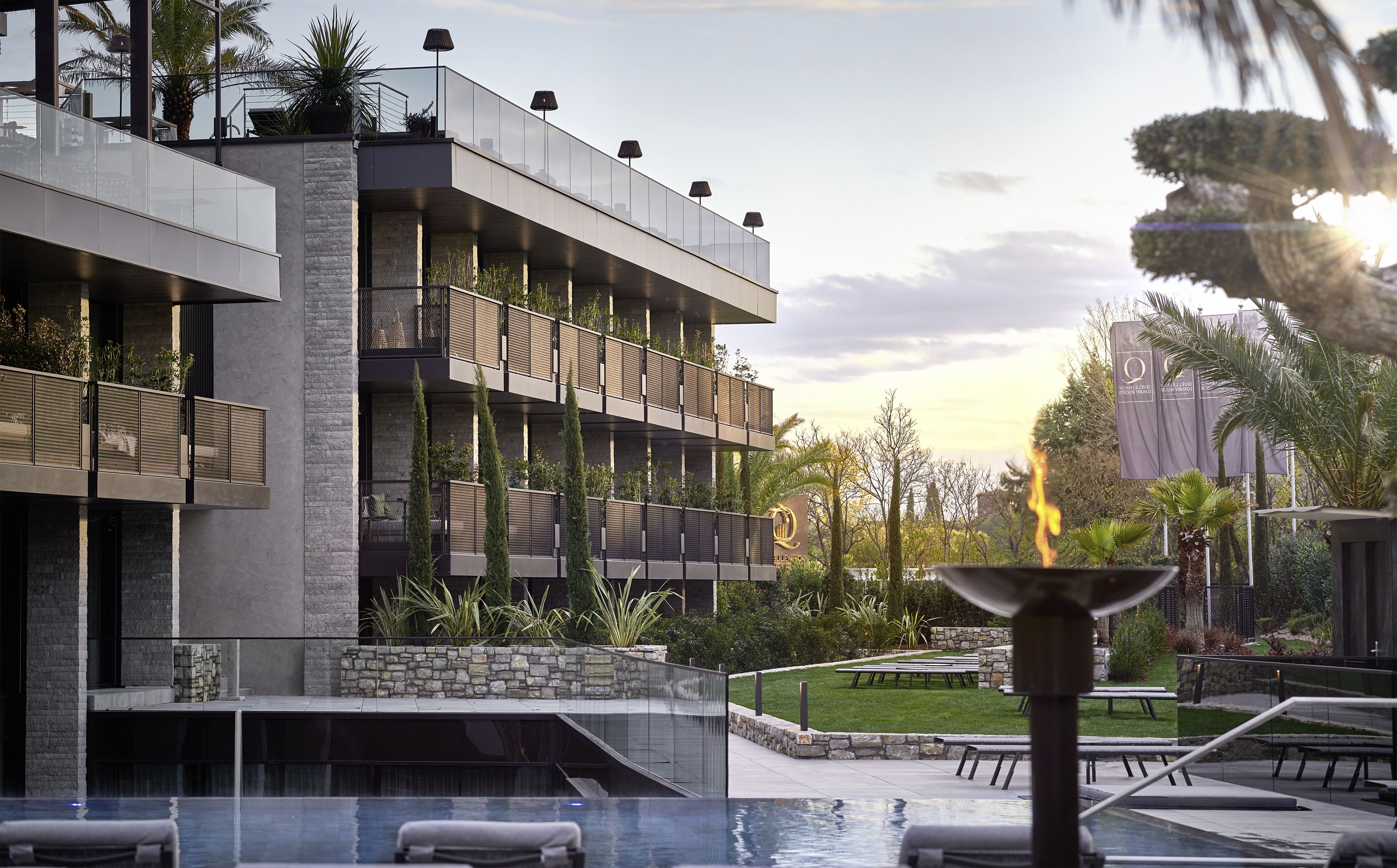 A modern building with multiple balconies, a pool area, and outdoor seating.