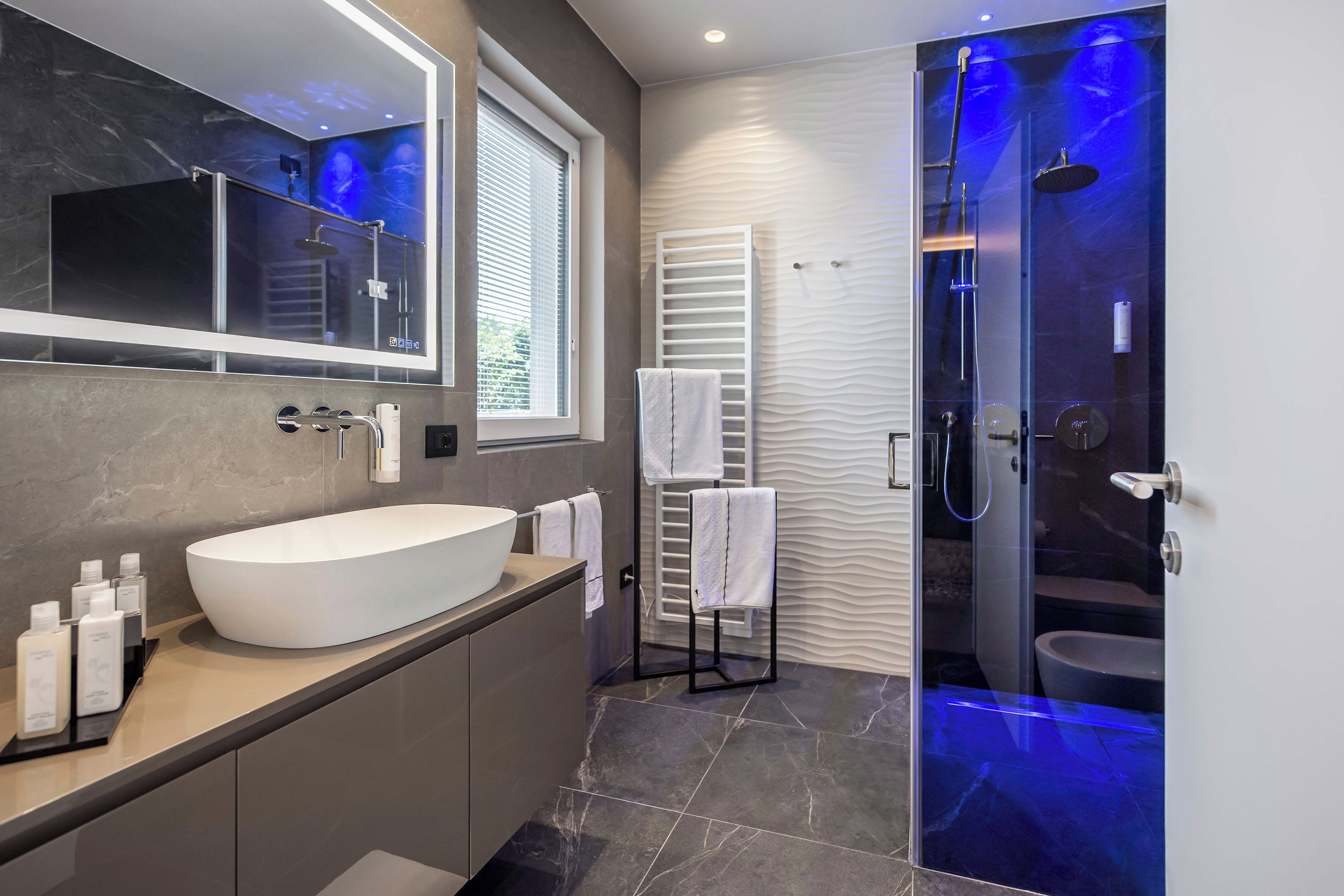 Un baño moderno con un lavabo grande de color blanco, una ducha con cerramiento de vidrio y un espejo sobre el lavabo.