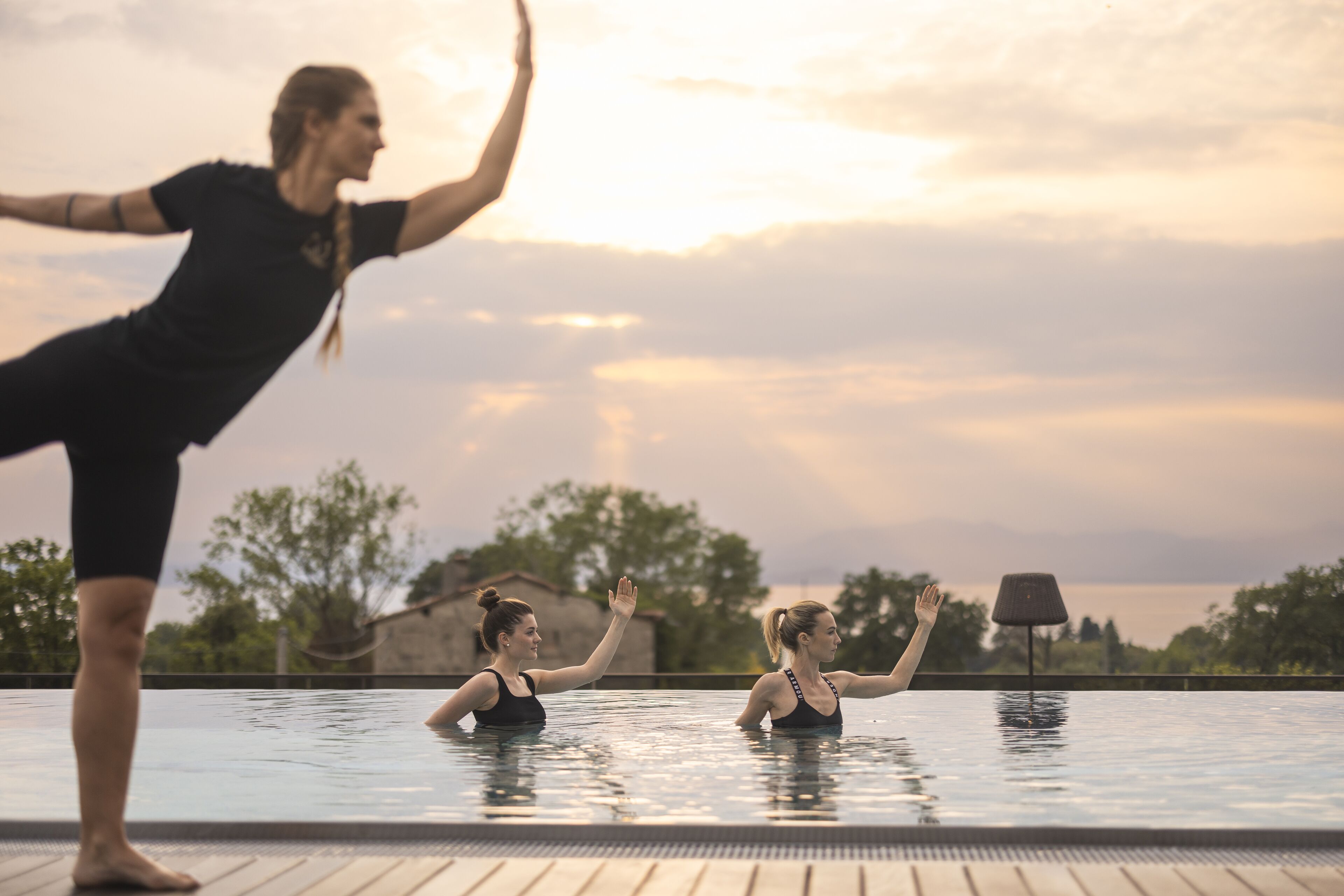 A swimming pool with two people practicing yoga.