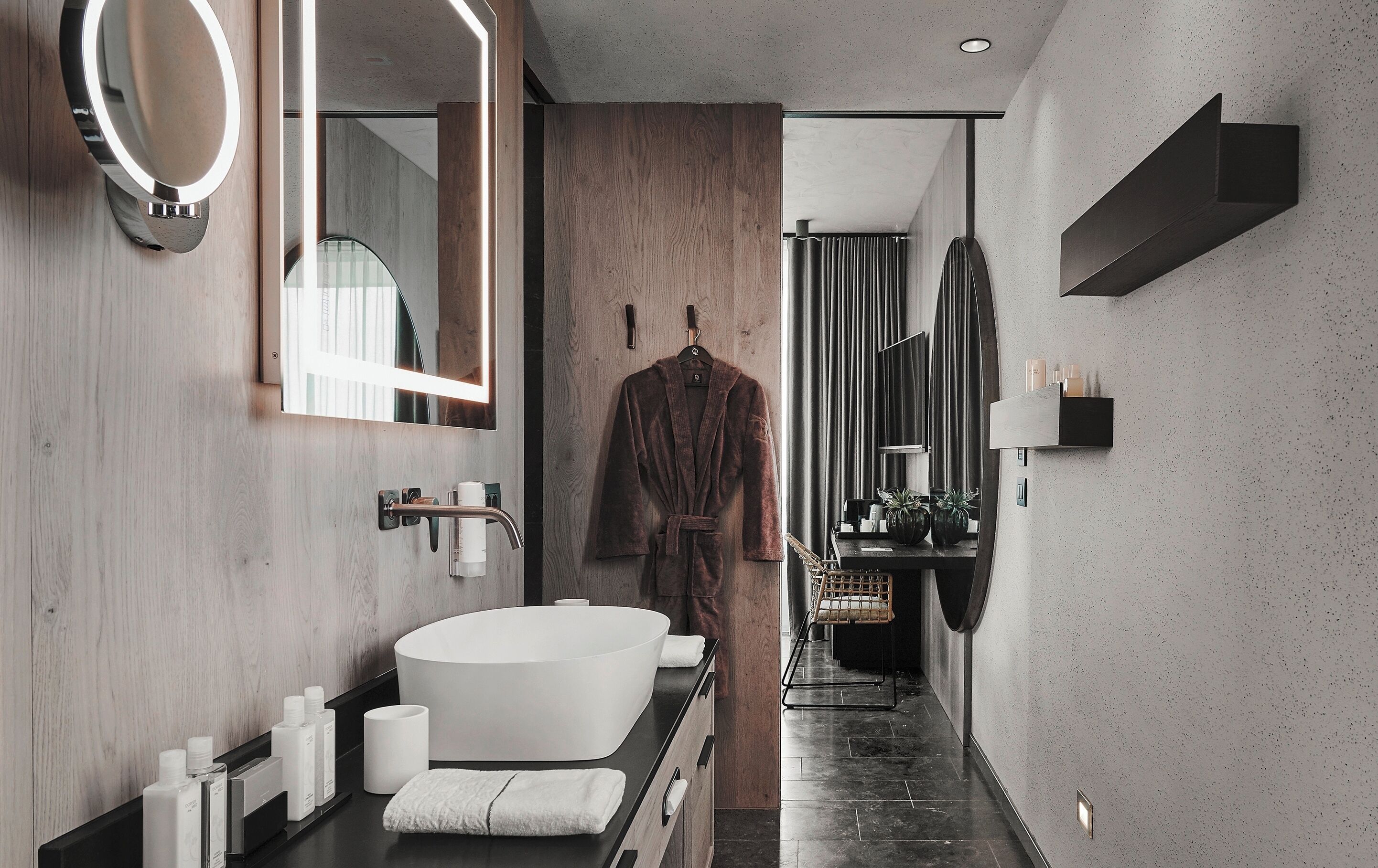 Un bagno moderno con una vasca da bagno ampia, un mobile contenitore in legno e un accappatoio su un appendiabiti.