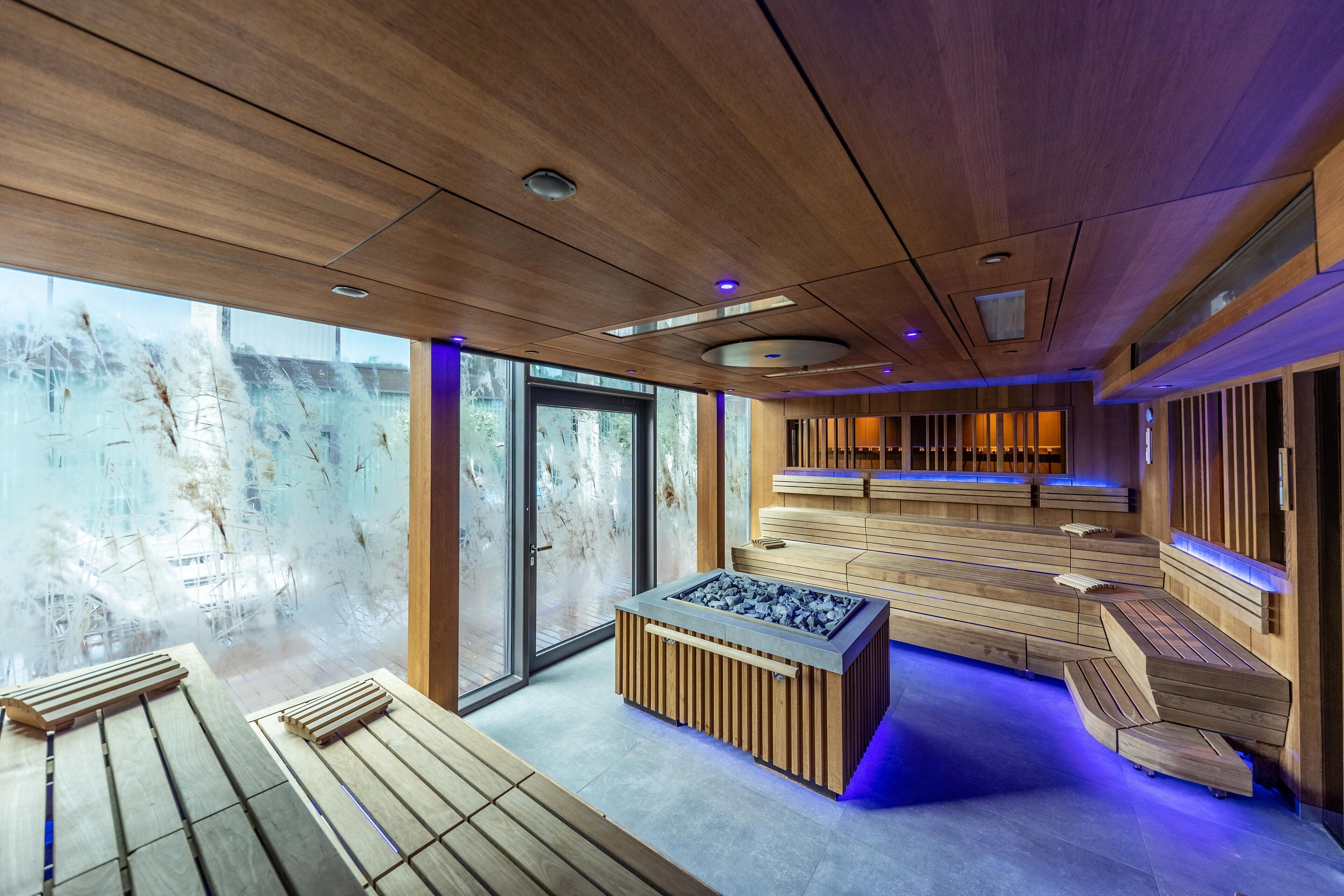 Een moderne spa-ruimte met houten banken en een centraal verwarmd stenen element.