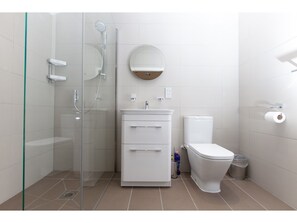 A modern bathroom with a glass-enclosed shower, a white sink with a mirror, and a toilet.