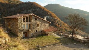 A stone house with a balcony, a small attached structure, and a staircase leading to the entrance. - Alberg Rural El Negre - Hostel (Ogassa)