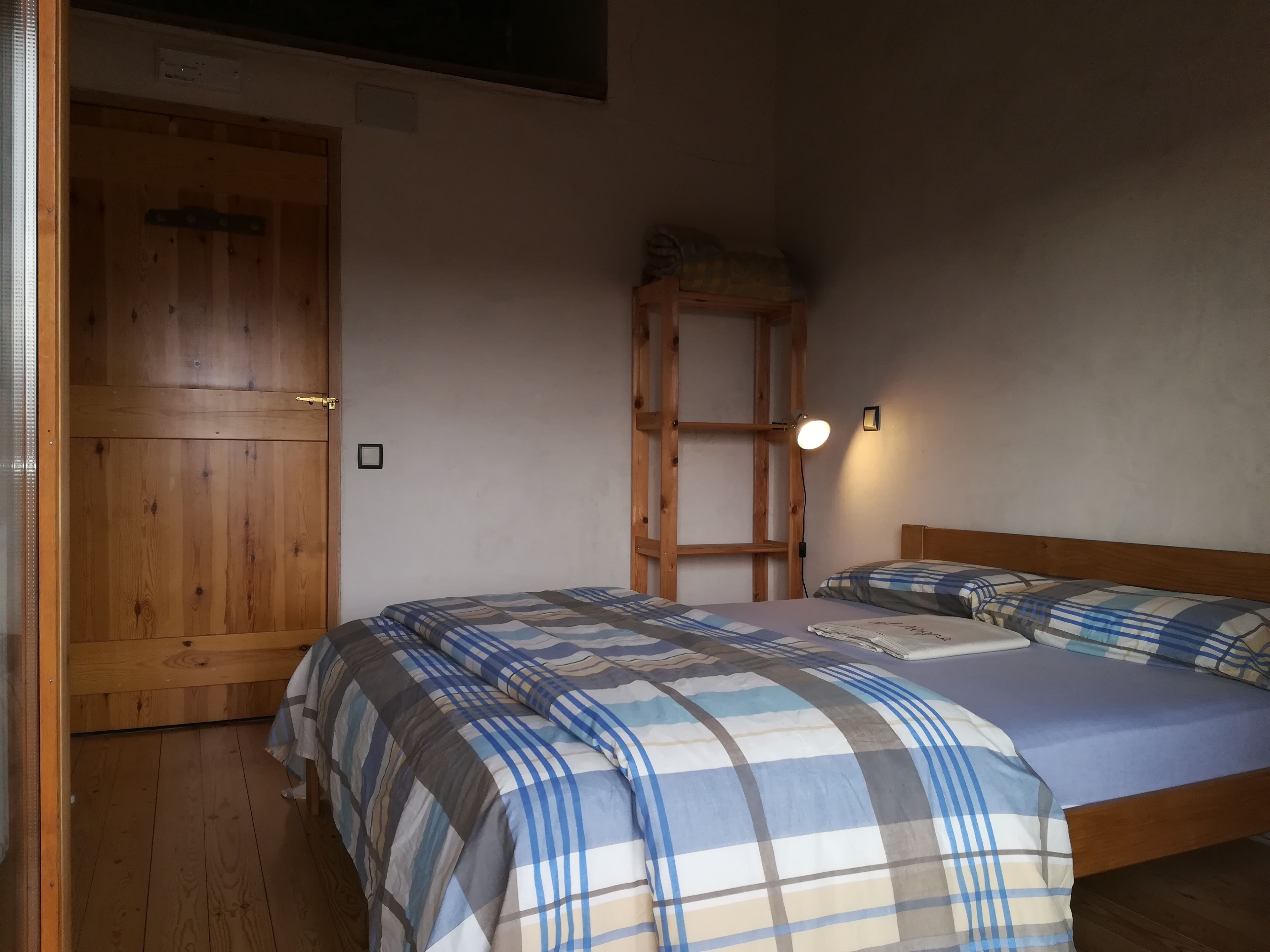 Un dormitorio con un armario de madera, una escalera y una cama con edredón escocés.