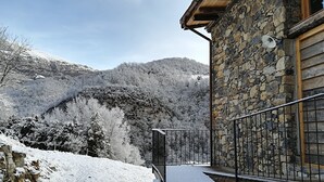 A stone building with a wooden balcony and a metal railing. - Alberg Rural El Negre - Hostel (Ogassa)