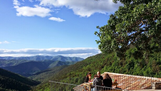 A scenic overlook with a stone platform and metal railing, surrounded by lush greenery and distant mountains. - Alberg Rural El Negre - Hostel (Ogassa)