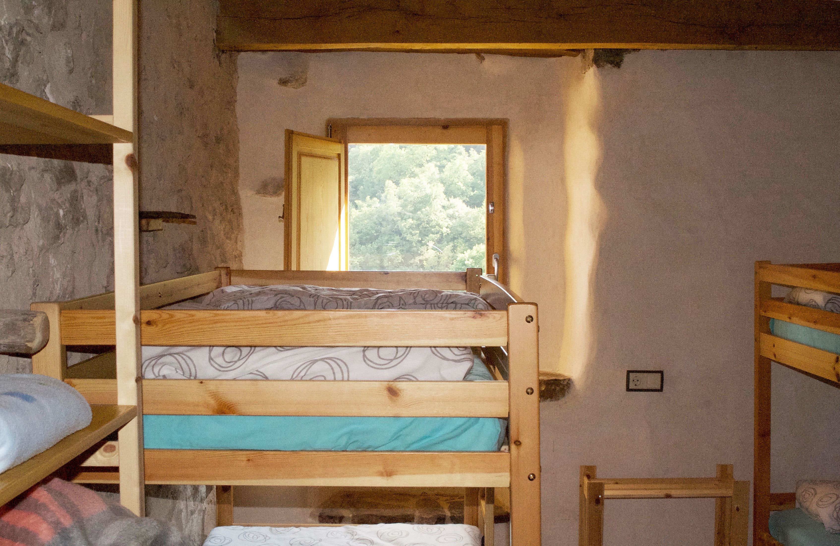 Dormitorio con literas, ventana, paredes de madera y una mesita.