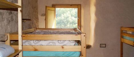 Dormitorio con literas, ventana, paredes de madera y una mesita.