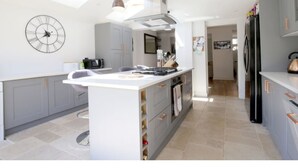A modern kitchen with a central island, grey cabinets, a large clock, and a skylight. - Modern, Chic 2BR Townhouse in Central Oxford (Oxford)
