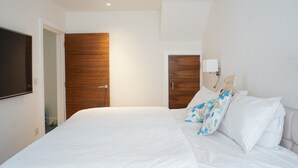 A modern bedroom with a large bed, wooden wardrobe, and a flat-screen TV mounted on the wall. - Modern, Spacious 2BR Flat in Oxford (Oxford)