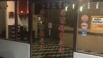 A hotel entrance with glass doors, a checkered floor, and a sign prohibiting drugs.