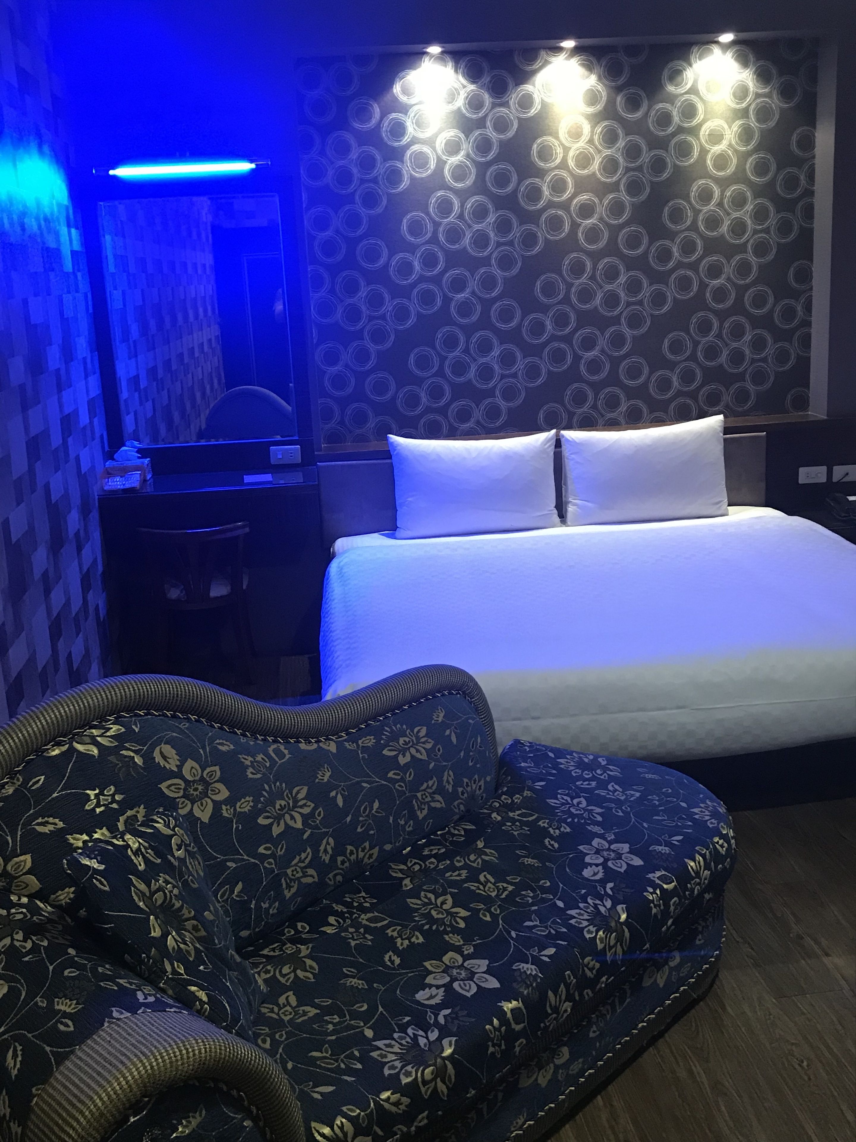 A hotel room with a bed, a desk, and a sofa.