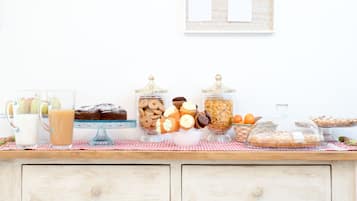 Un buffet de petit-déjeuner proposant diverses pâtisseries, un coin café et un tableau d’affichage au mur.