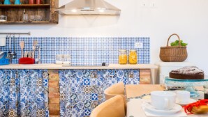 Una cocina con salpicadero de azulejos, estantes de madera y un colgador para ollas.