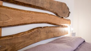 Una cama con cabecera de madera y una manta con textura.