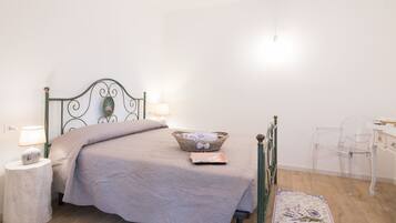 Um quarto bem arrumado com uma cama, luminárias de cabeceira, mesa de cabeceira, uma cadeira e um tapete pequeno.