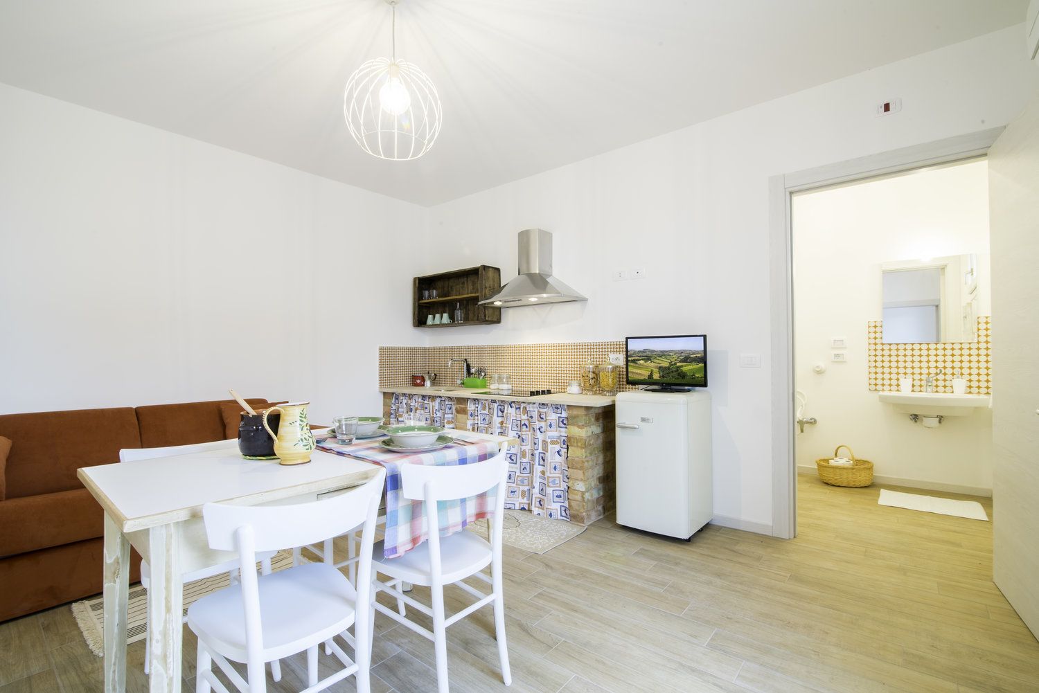 Un espacio habitable compacto con comedor, kitchenette y baño pequeño.