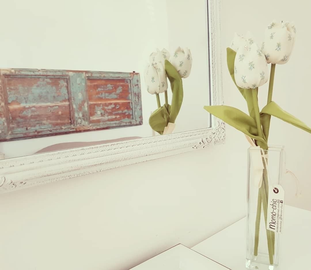A vase with white flowers on a white surface.
