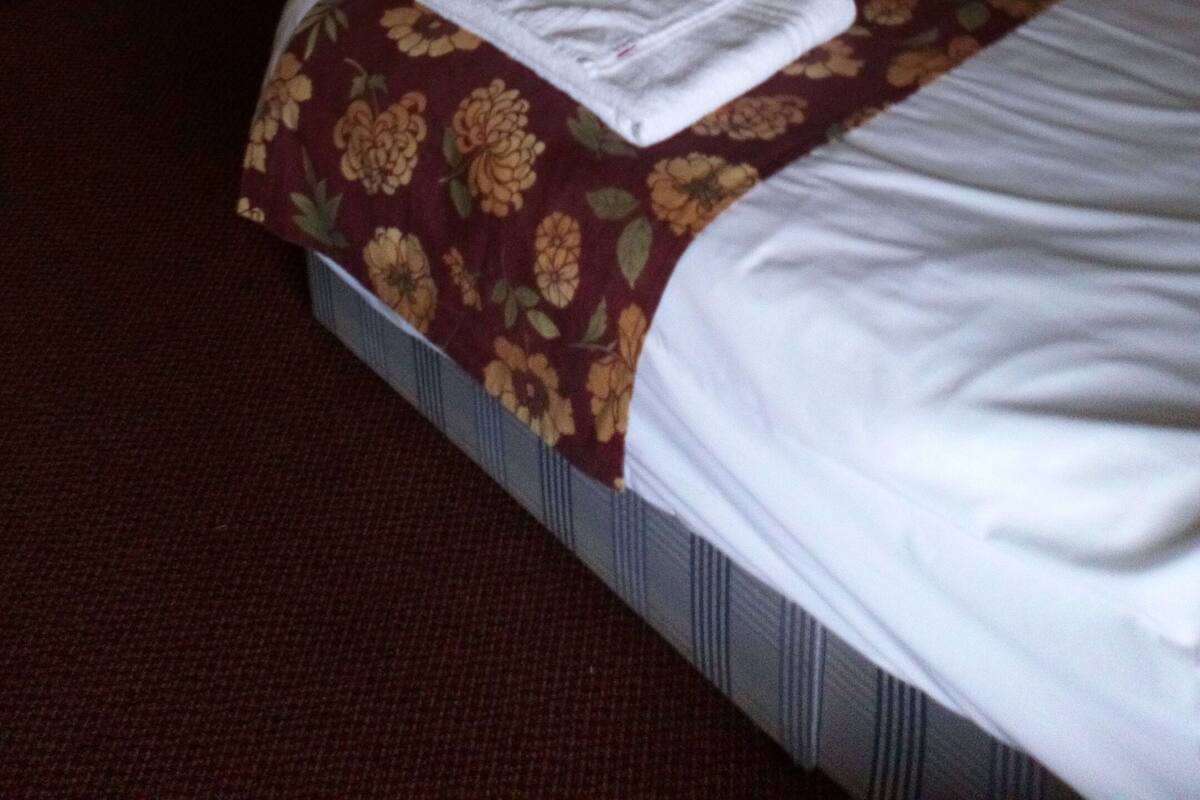 A hotel room with two beds, a wooden nightstand, a mirror, and a wall-mounted air conditioning unit.