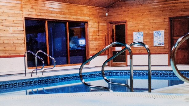 Una piscina interior con paredes de madera y techo inclinado.