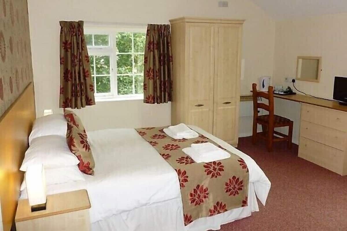 A bedroom with a bed, a desk, a chair, and a wardrobe.