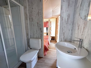 Baño con inodoro, lavabo y zona de ducha.