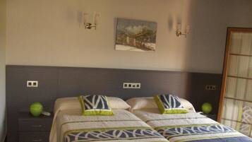 A bedroom with two beds, a nightstand, a green vase, and a painting on the wall.