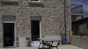 A stone building with a patio area featuring a table and chairs. - Chez Mary (Vanosc)