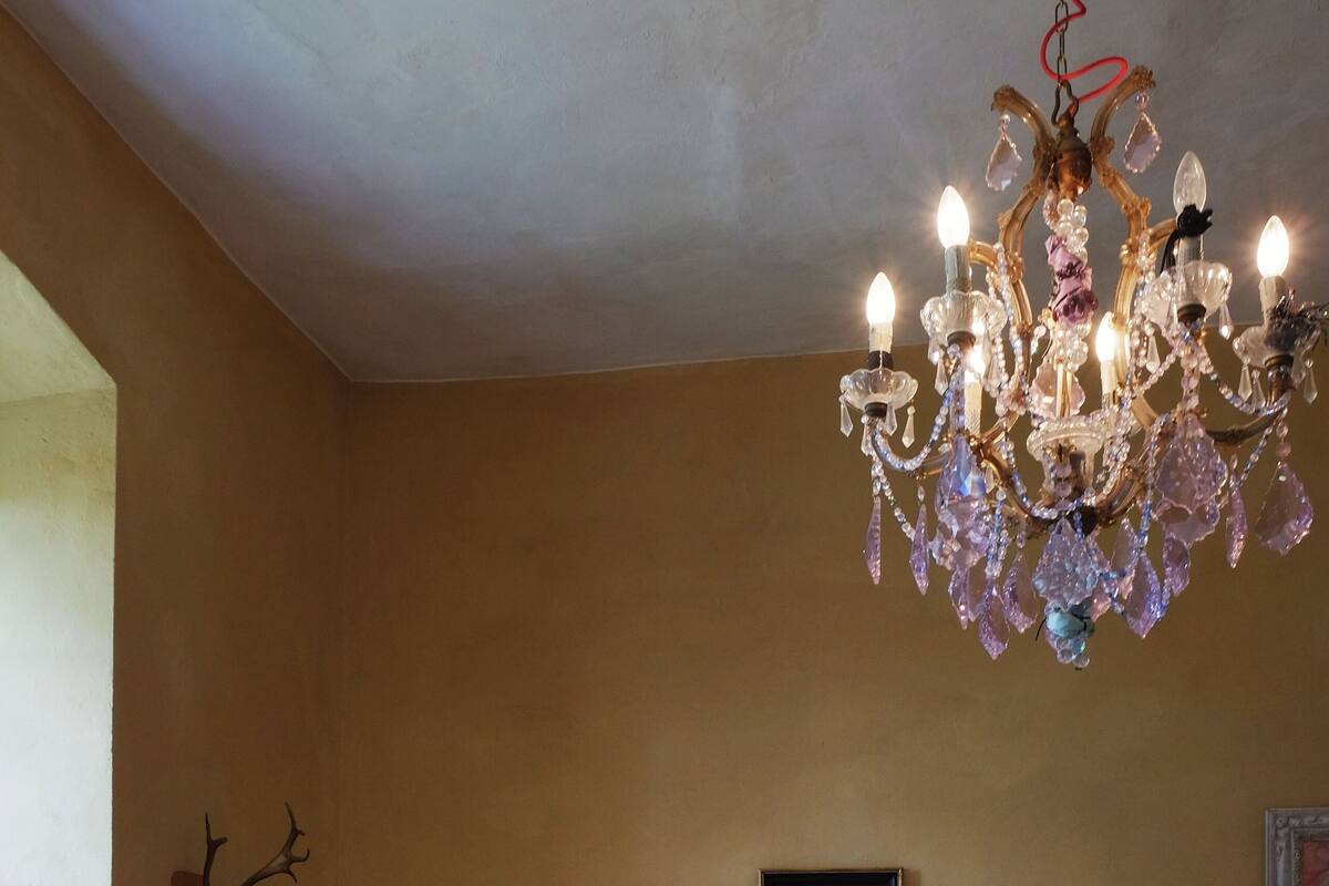 Une pièce comprenant un canapé à motifs floraux, deux fauteuils décoratifs, une table ronde et un lustre.