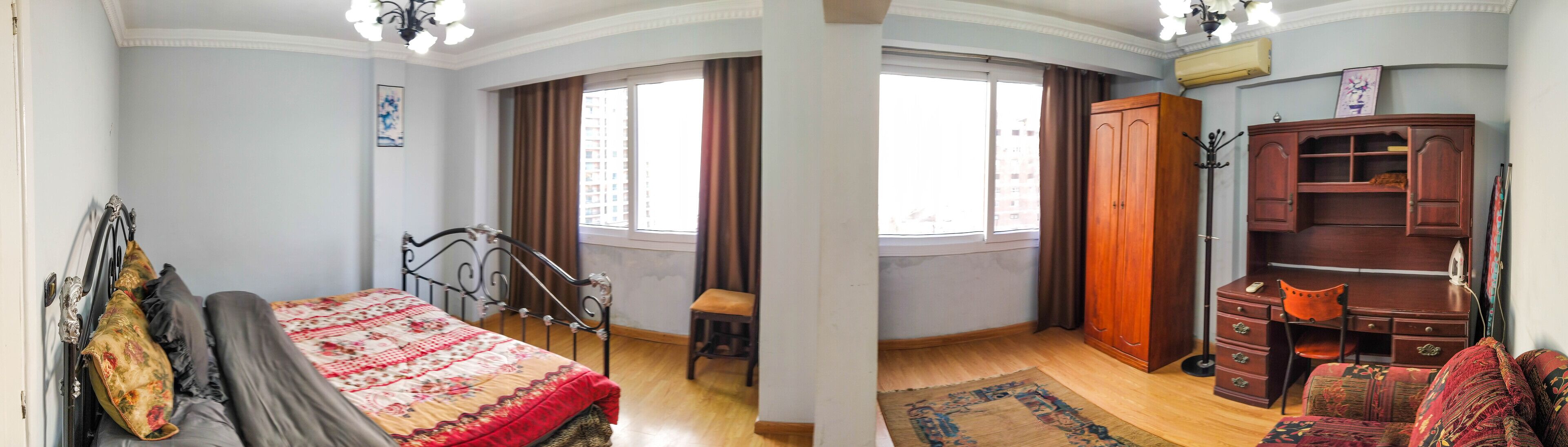 Un dormitorio con cama, una silla, un escritorio y un armario.