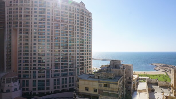Un grand hôtel à plusieurs étages, avec vue sur la mer et une plage en arrière-plan.