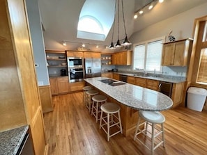 A modern kitchen with a central island, wooden cabinets, and a built-in oven.