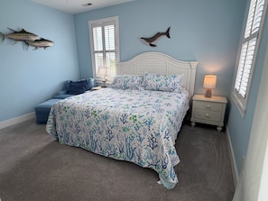 A bedroom with a bed, nightstand, and decorative fish on the wall.