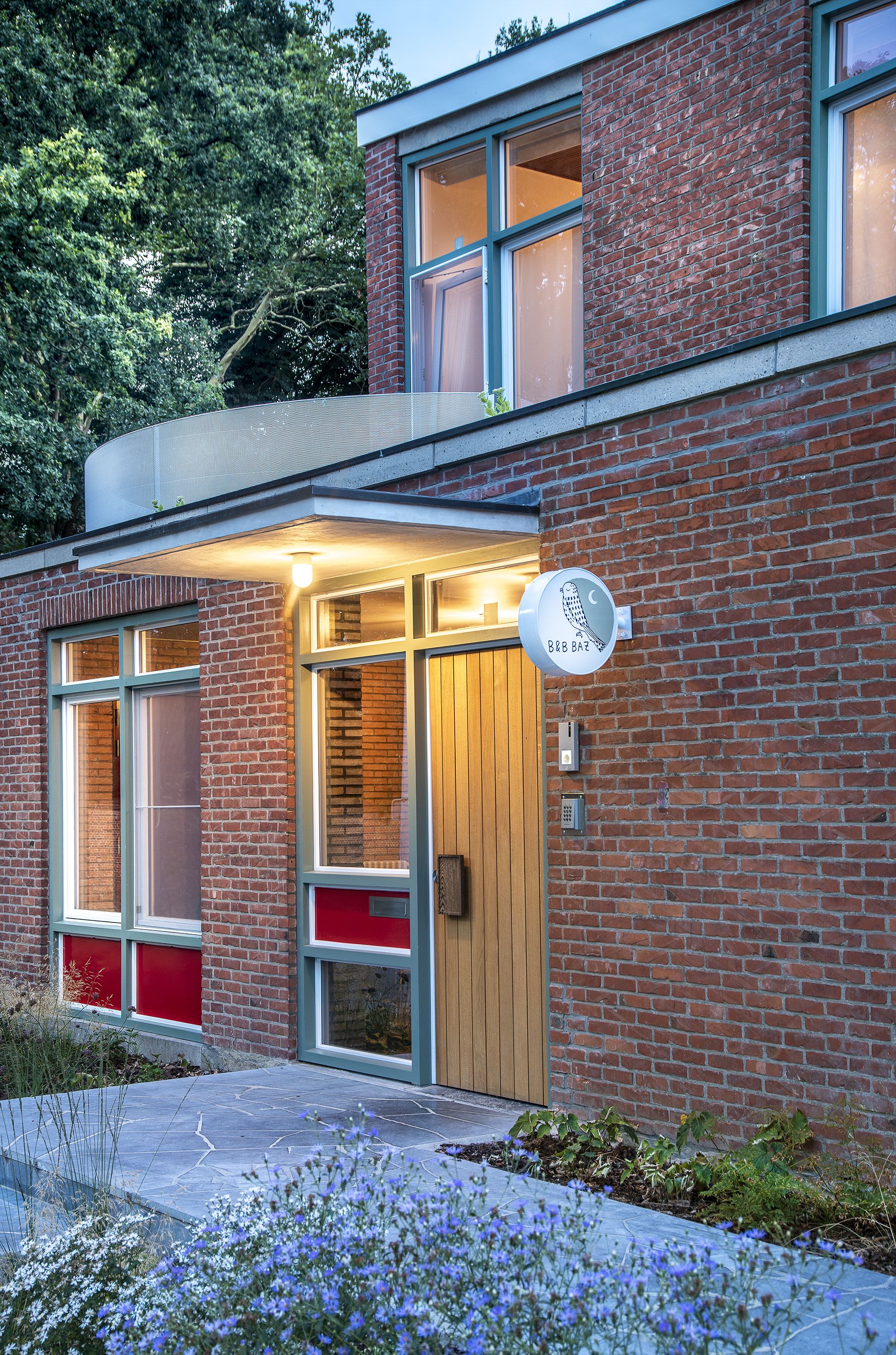 A modern building with a brick facade, large windows, and a wooden door.
