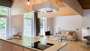 Una cocina moderna con una isla central, electrodomésticos integrados y una lámpara colgante.