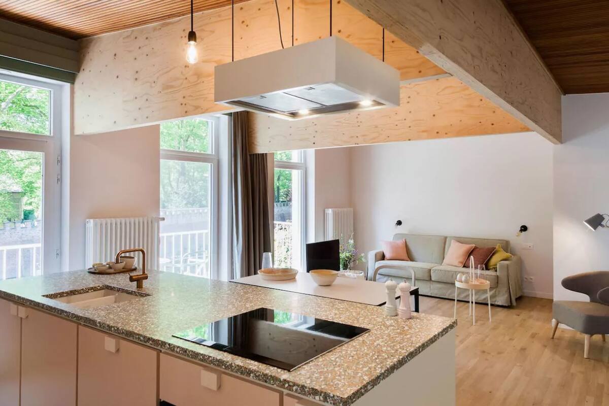 A modern kitchen with a central island, built-in appliances, and a pendant light.