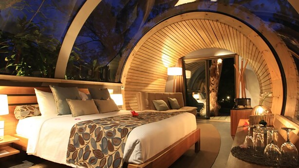 A circular, wooden-framed bedroom with a bed, bedside tables, and a nightstand. - Bubble Lodge Ile aux Cerfs (Trou d'Eau Douce)