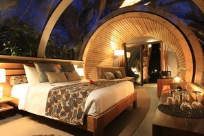 A circular, wooden-framed bedroom with a bed, bedside tables, and a nightstand. - Bubble Lodge Ile aux Cerfs (Trou d'Eau Douce)