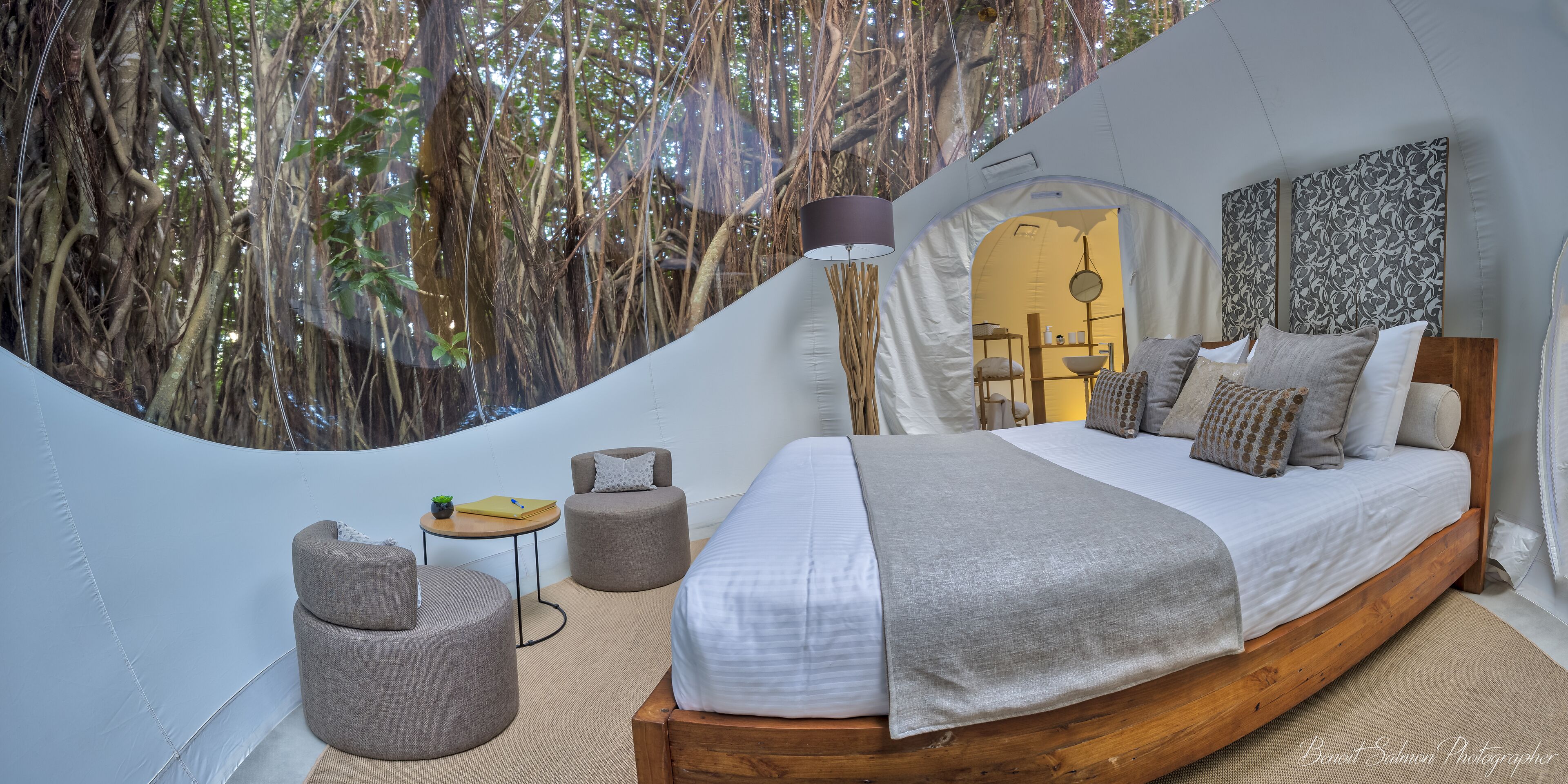 A cozy, treehouse-style bedroom with a bed, bedside tables, and a hanging lamp.