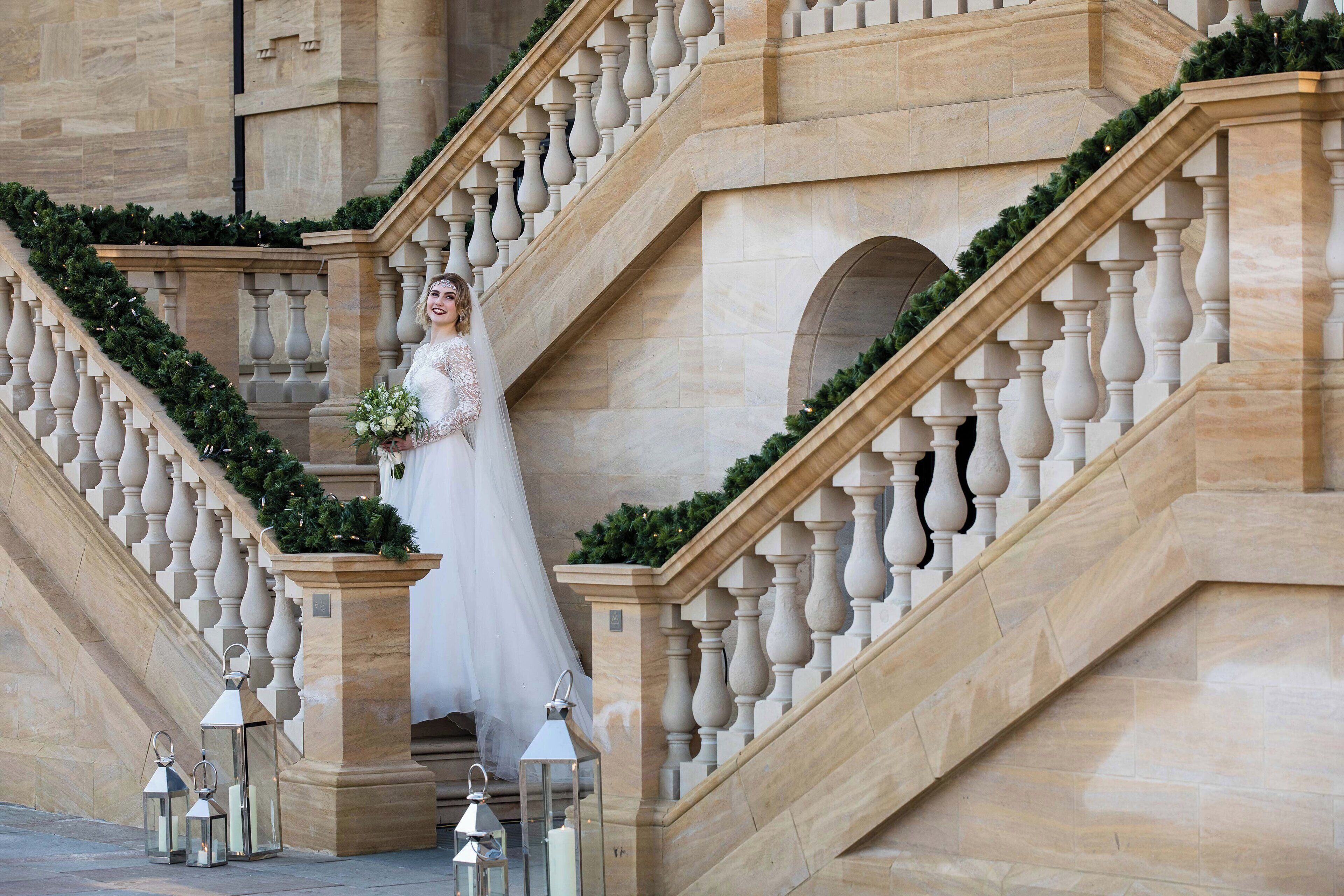 A grand staircase with a balustrade, a bride descending, and decorative lanterns at the base.