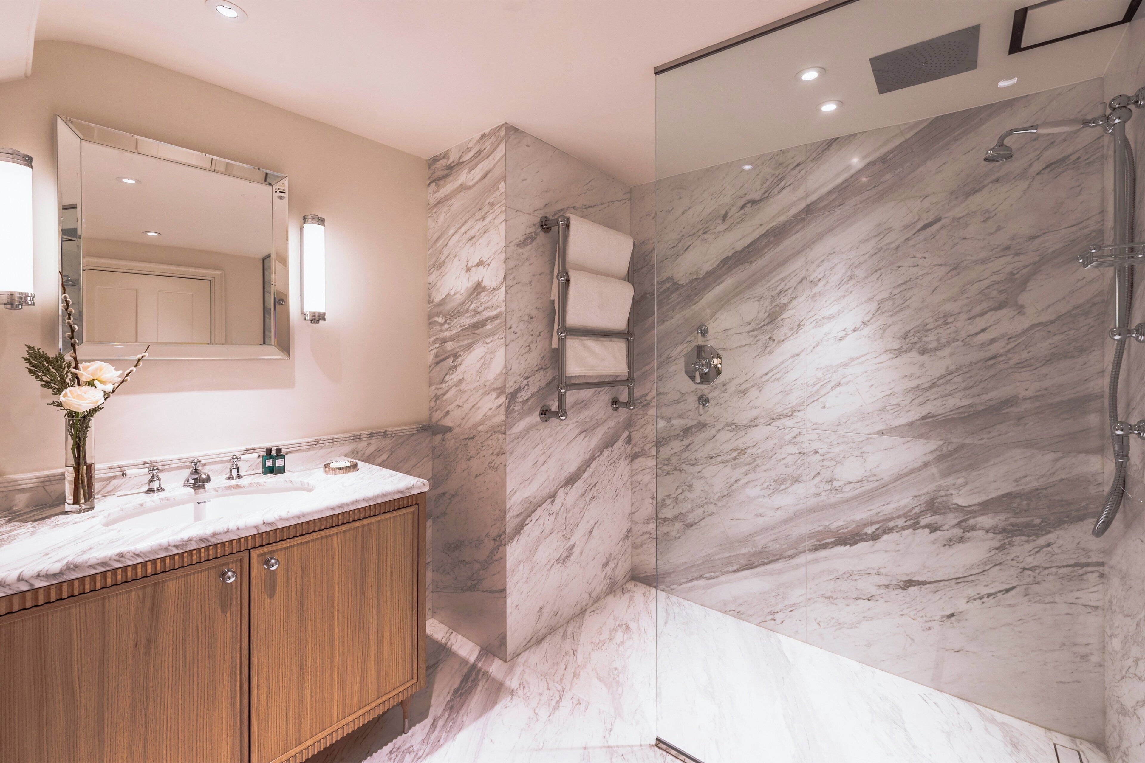 Une salle de bain moderne avec un meuble-lavabo en marbre, une cabine de douche en verre et un grand miroir.