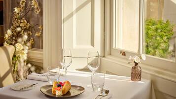 A dining table set with a plate of food, wine glasses, and cutlery.