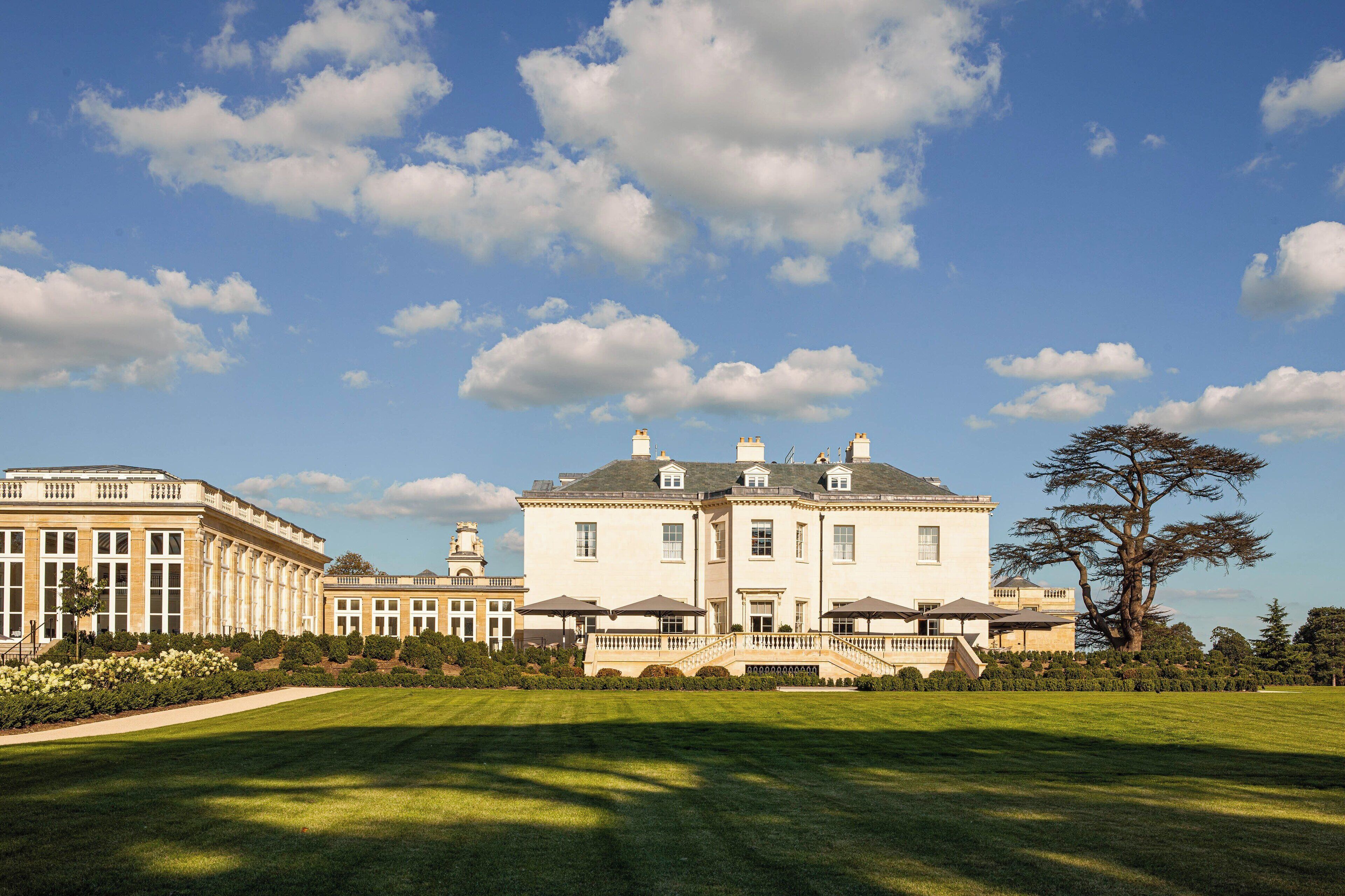 Un grand bâtiment imposant, doté d’une façade symétrique, de nombreuses cheminées et d’une entrée centrale avec un escalier.