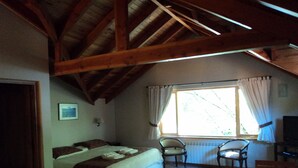Una camera da letto con un letto, una sedia, un tavolo e una finestra con tende.