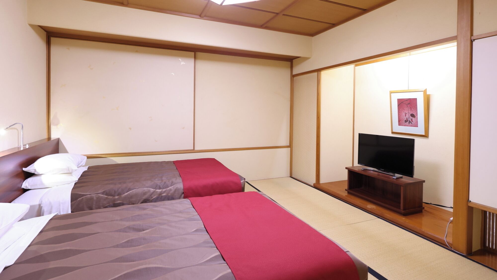 Habitación de hotel con dos camas, televisión y puertas correderas.