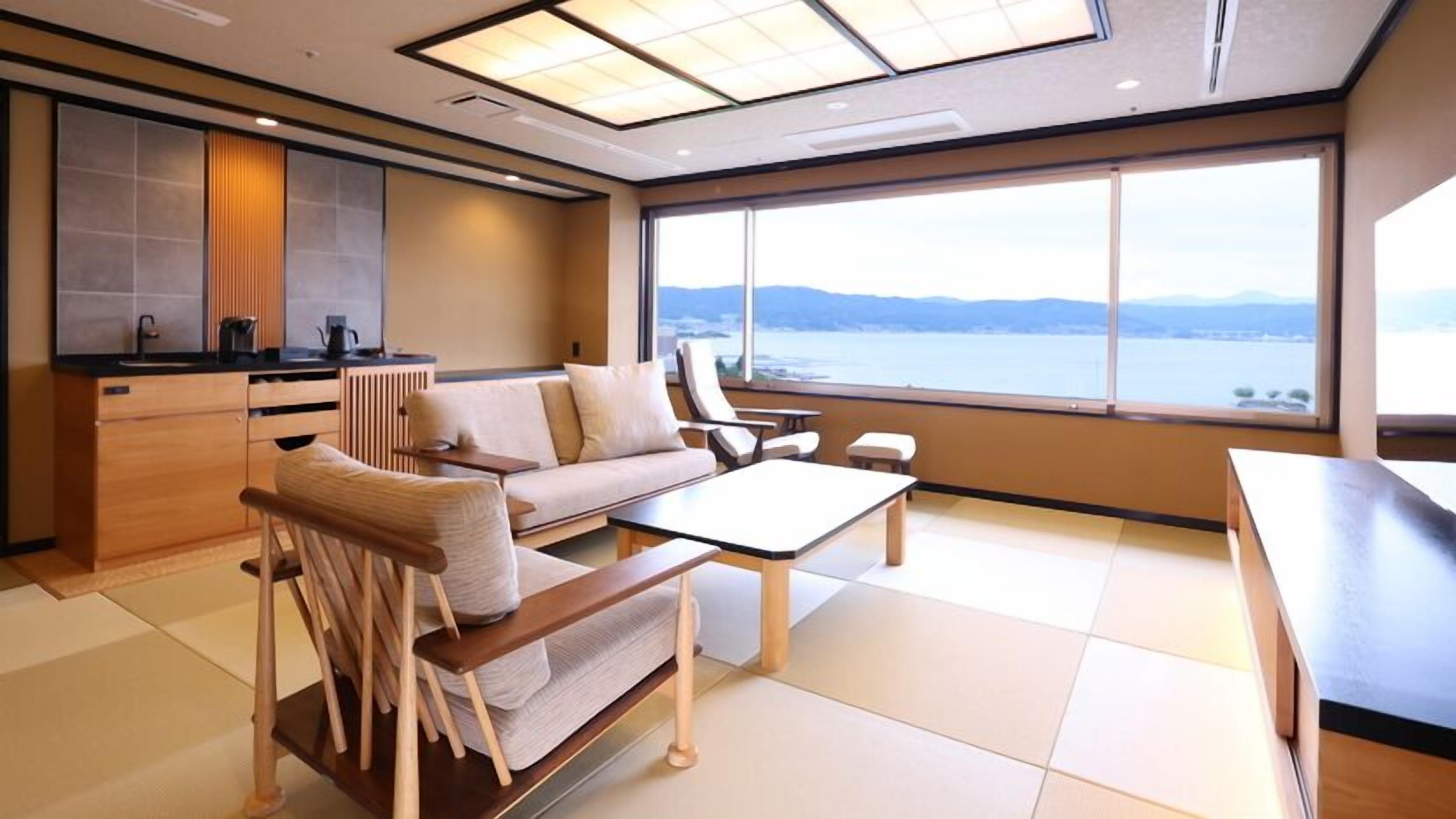 Un interior moderno con un sofá, sillas, una mesa y vistas a un cuerpo de agua.