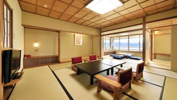 Una stanza tradizionale giapponese con pavimento in tatami, un tavolino e cuscini rossi.