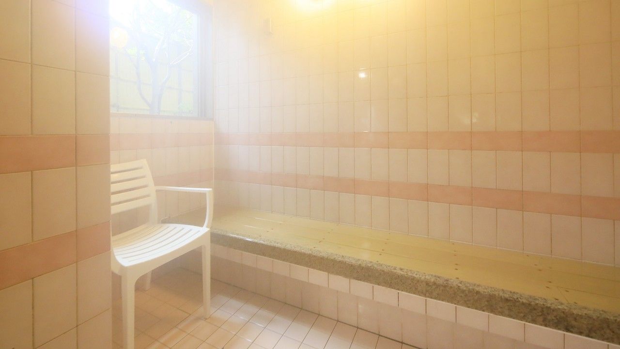 A bathroom with a bench, tiled walls, and a window.