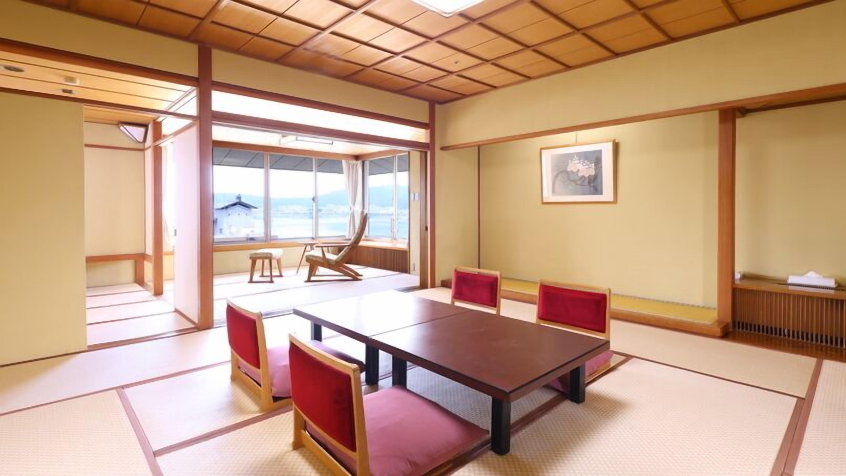 Una habitación japonesa tradicional con suelo de tatami, una mesa baja y cojines rojos.